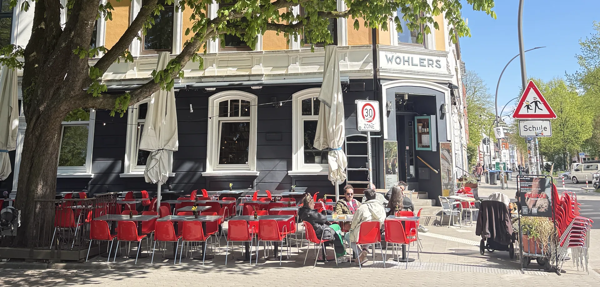 Sonnige Fassade und Terrasse des WOHLERS unter grünen Bäumen