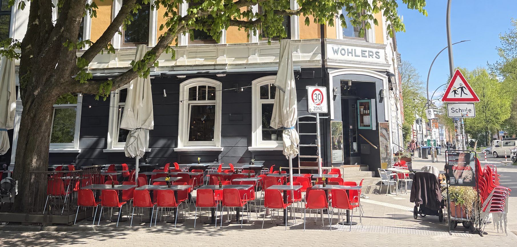 Sonnige Fassade und Terrasse des WOHLERS unter grünen Bäumen